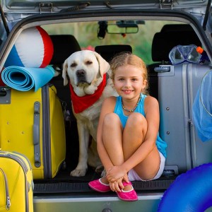 travelling-with-pets-young-girl-and-her-labrador-sitting-in-car-boot