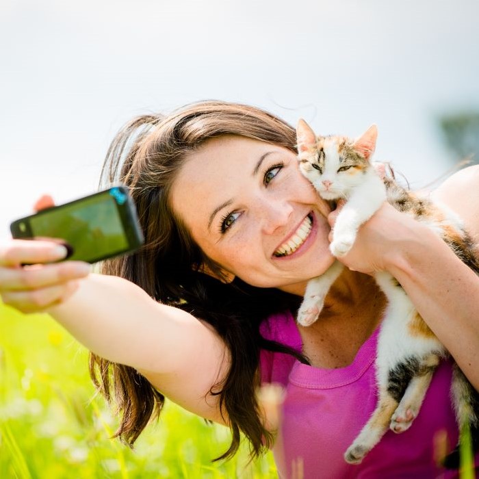 Woman taking photo with mobile phone camera of herself and her cat – outdoor in nature (2)