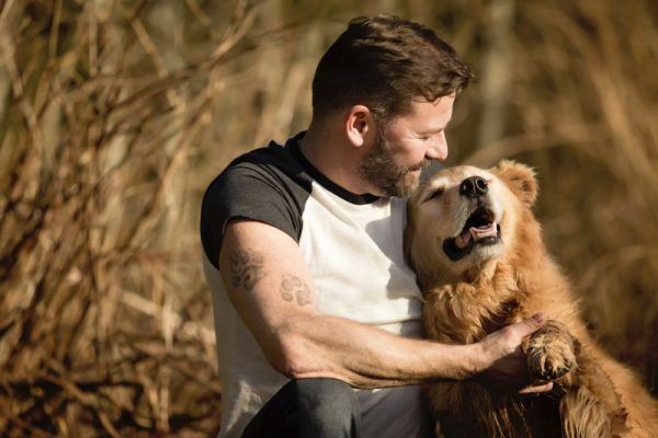 Male owner and golden retriever sharing a cuddle
