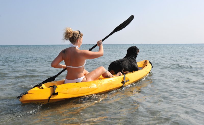 young woman and her rottweiler on a sea kayak