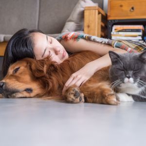 Pet parent cuddling their dog and cat at home